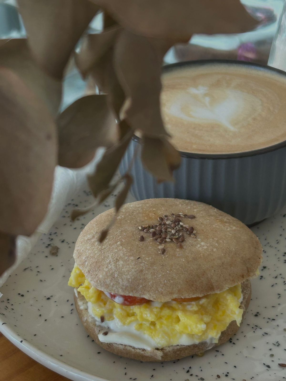 Pan árabe con queso crema, huevo revuelto y cherrys, junto a un café con leche de Antojitos Tandil