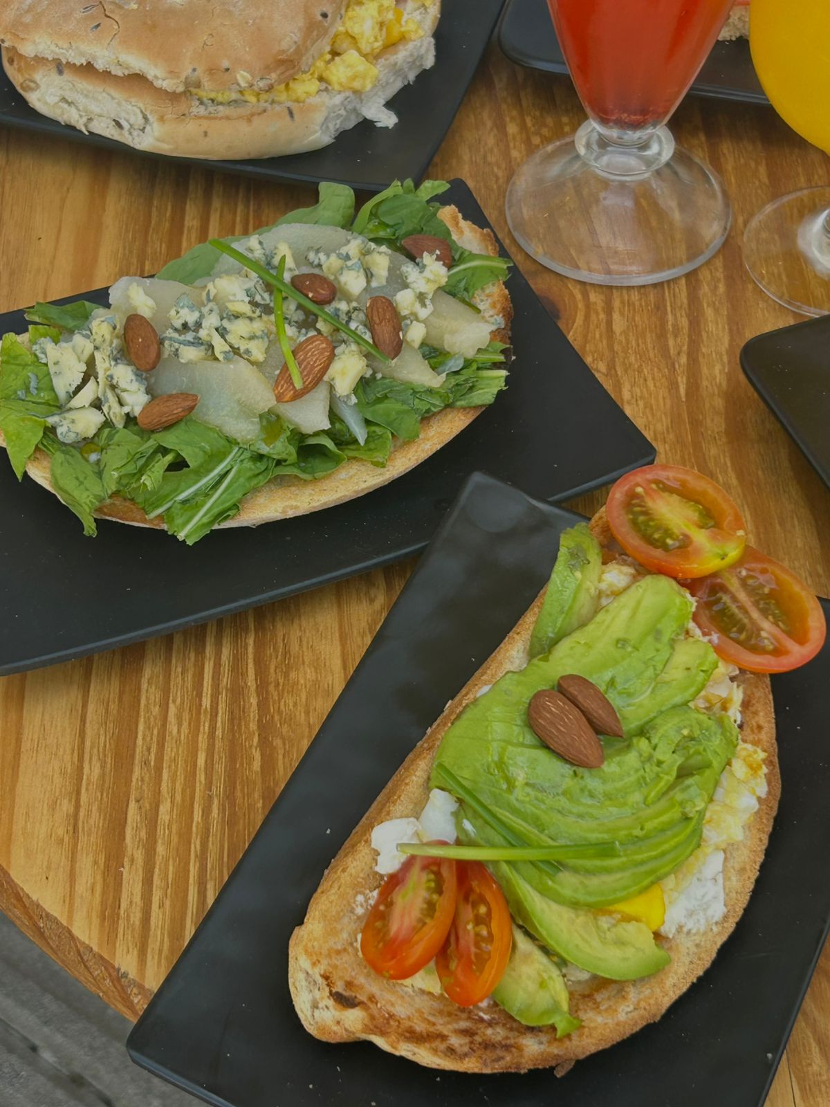 Tostón de rúcula, queso azul, peras y almendras y tostón de palta, queso crema y tomates cherry sobre pan de campo