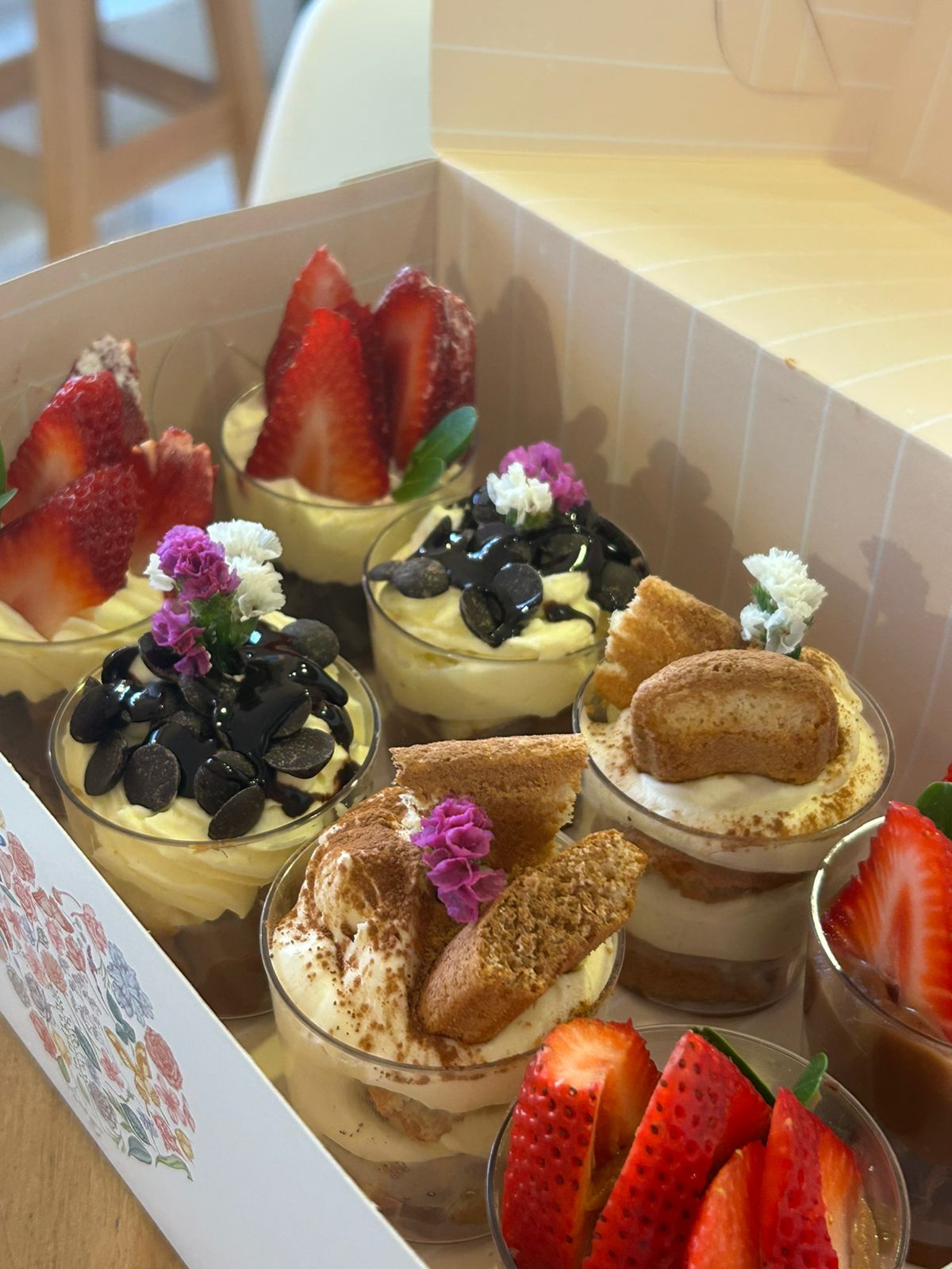Dessert cups with strawberries, Oreo and edible flowers in a sweet table box