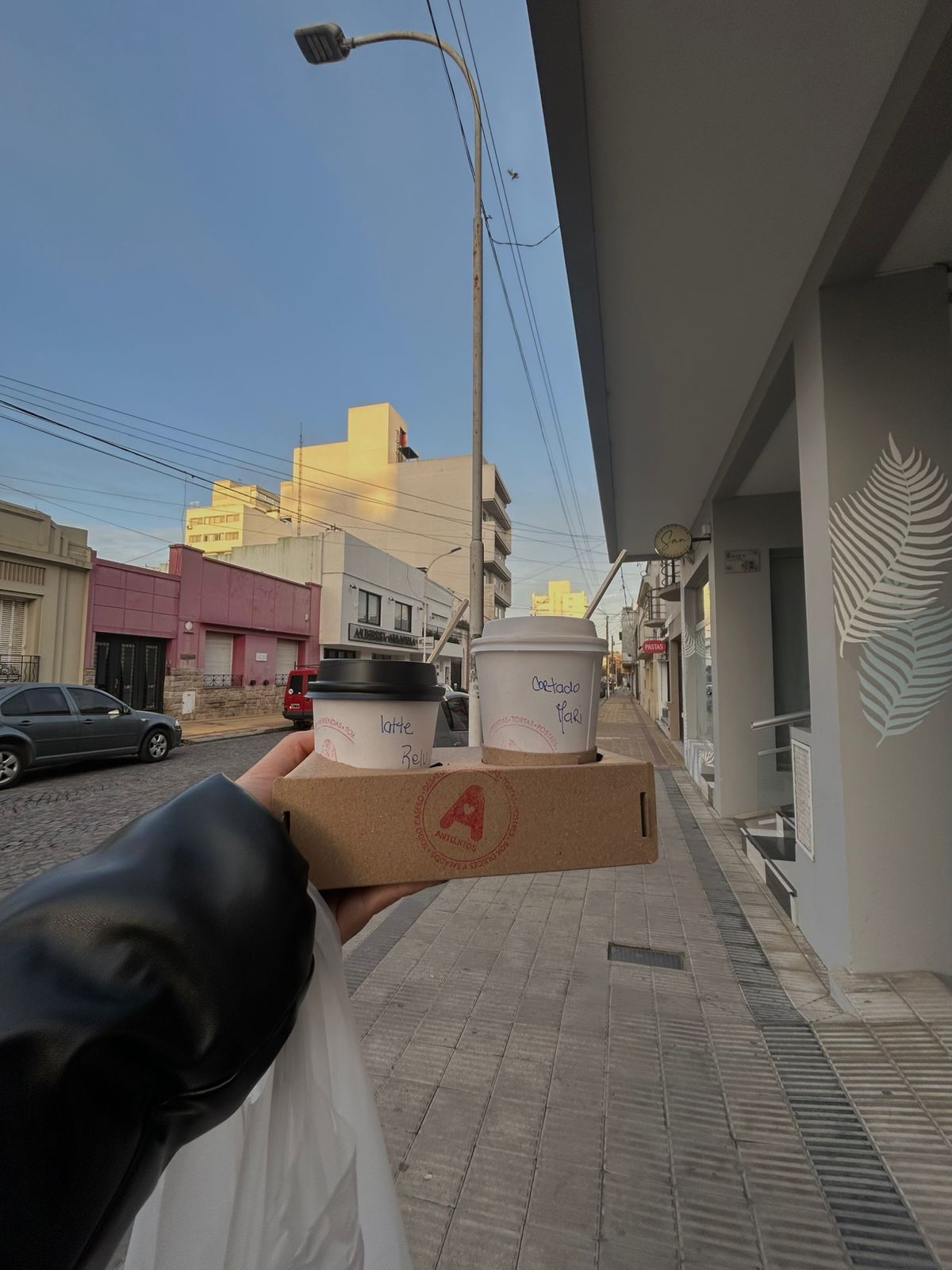 Dos cafés para llevar de Antojitos en su portavasos, en una calle de Tandil