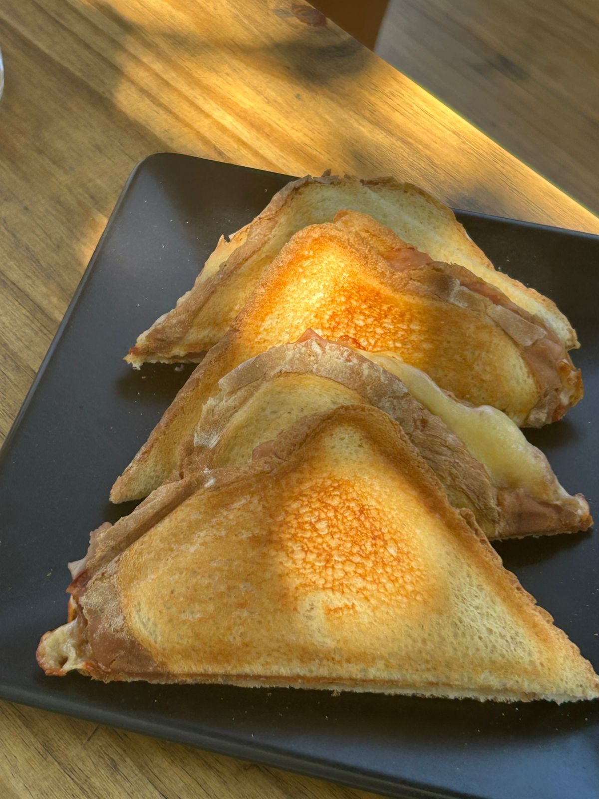 Golden toasted sandwiches on a black plate